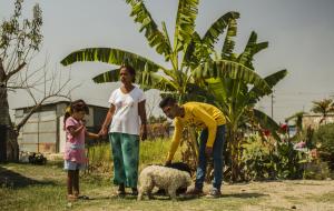 Wuilly, mother and little sister with thier dogs in front of two banana trees 